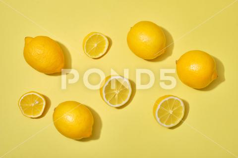 A top view shot of with halves and whole ripe lemons on yellow background background, citron, citrus, closeup, collection, color, design, diet, food, fresh, freshness, fruit, green, group, health, healthy, ingredient, isolated, juice, juicy, leaves, lemon, lemonade, macro, natural, nature, object, orange, organic, part, piece, raw, ripe, round, section, set, slice, sour, sweet, tropical, vegetarian, view, vitamin, white, whole, yellow