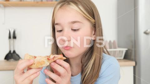 Young family deliciously eating Italian pizza, sitting in the kitchen at the table, they communicate and have fun. Fast food lunch {appetite,caucasian,pizza,portrait,smile,happy,family,people,eating,table,appetizing,cooked,cook,delicious,delivery,dinner,nutrition,many,tomato,tasty,supreme,spicy,organic,pastry,fast food,boy,biting,childhood,children,daughter,happiness,girl,cheese,group,hand,human,together,snack,share,service,plate,pizzeria,hungry,eat pizza,face,beautiful,diet,tasty snack,young}