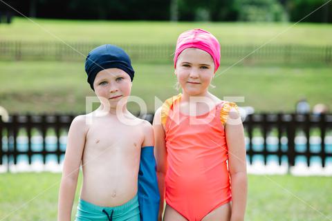 Adorable little sister and brother in swimwear and hats standing on green grassy lawn at poolside and looking at camera during summer vacation children, together, poolside, lawn, vacation, summer, sister, brother, portrait, childhood, pool, sibling, kid, swimwear, hat, resort, holiday, adorable, meadow, carefree, summertime, innocent, chill, girl, boy, swimsuit, shorts, grassy, season, relationship, yard, cute, harmony, daytime, sunlight, idyllic, friendship, nature, outdoors, looking at camera, blurred background, vertical