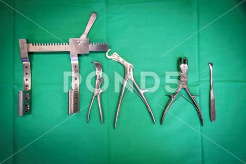 Some surgical rib instruments lie on a green surgical cloth foot, radiology, abdomen, adhesive plaster, aid kit, analysing, analysis, ankle, anvil, apparatus, appearance, astragal, axis, background, bandage, basin, body, caliper, care, cervical, clavicle, coast, column, contrast, diagnose, doctor, drill, education, elbow, embankment, envision, exam, examine, first aid, fractured, front, frontend, hospital, instrument, medicals, ray, rib, ribs, skeleton, sternum, surgery, surgical, surgical instrument, surgical scissor, thorax