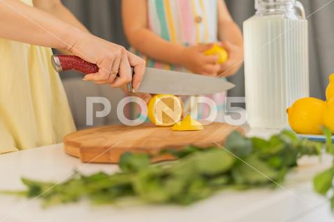 Hands of woman cutting lemons and oranges on table at home woman, hand, food, fruit, kitchen, citrus, prepare, cut, vegetarian, sharp knife, female, homemade, raw, carefully, cook, cutting board, delicious, shallow depth of field, slice, lemonade, closeup, knife, wooden, nutrition, safety, diet, healthy, mother, chef, lemon, hands, health, table, daughter, fresh