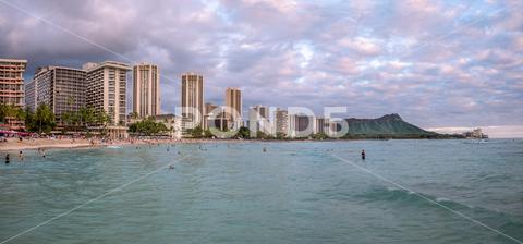 Honolulu, Hawaii - December 29, 2022: View of Waikiki Beach with Diamond Head valcano in the distance. architecture, beach, building exterior, city life, cityscape, coastline, diamond head, dusk, famous place, hawaii, hawaii islands, honolulu, hotel, island, landscape scenery, mountain, oahu, ocean, outdoors, pacific islands, pacific ocean, panorama, panoramic, relaxation, royal hawaiian hotel, sand, sea, sky, tourism, tourist, travel, travel destinations, trees, tropical, tropical climate, twilight, urban skyline, usa, vacation, waikiki, waikiki beach
