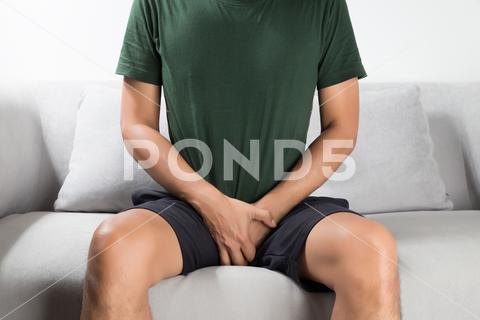 Asian man wants to pee and is holding his bladder. Painful Urination, Urinary, Incontinence, Prostate, Pain, Penis, Urinate, Dysuria, Testis, Urine, Piss, Ache, Testicle, Painful, Urination, Pee, Hold, Urethritis, Urinating, Urinal, Grab, Crotch, Urethra, Bladder, Genital, Disease, Tract, Infection, Cancer, Risk, Inflammation, Inflame, Hand, Symptom, Male, Men, Sit, Sofa, Gray, Restrain, Treatment, Prevention