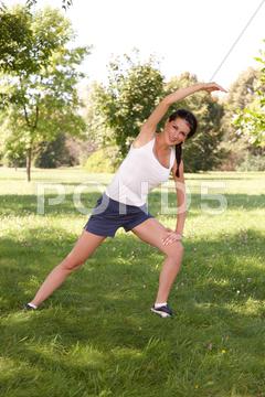 Young woman doing stretching exercise on green grass 20s, adult, attractive, beautiful, beauty, body, care, caucasian, exercise, fit, fitness, girl, grass, green, happy, health, healthy, leisure, life, natural, nature, outdoor, outdoors, outside, park, peaceful, people, person, pose, relax, relaxation, serene, slim, sport, sporty, standing, streching, trees, wellness, white, woman, workout, yoga, young