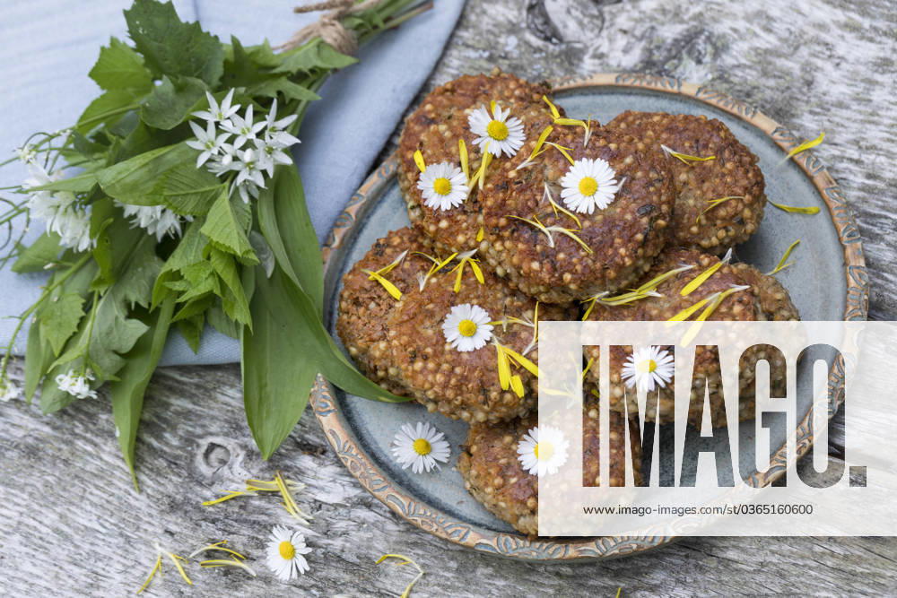 Selbstgemachte Kraeuterbratlinge mit Baerlauch auf einem Teller, dekoriert mit Gaensebluemchen selfmade herb patties with wild garlic on a plate, decorated with daisies BLWS698282