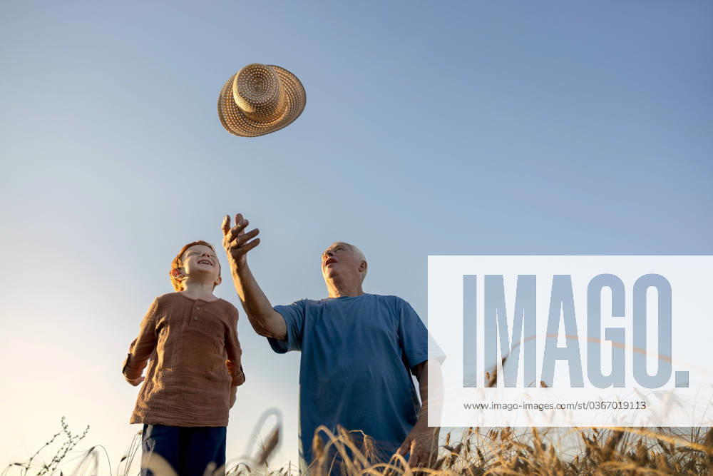 Grandson watching grandfather throwing straw hat under sky model released, Symbolfoto, MBLF00128