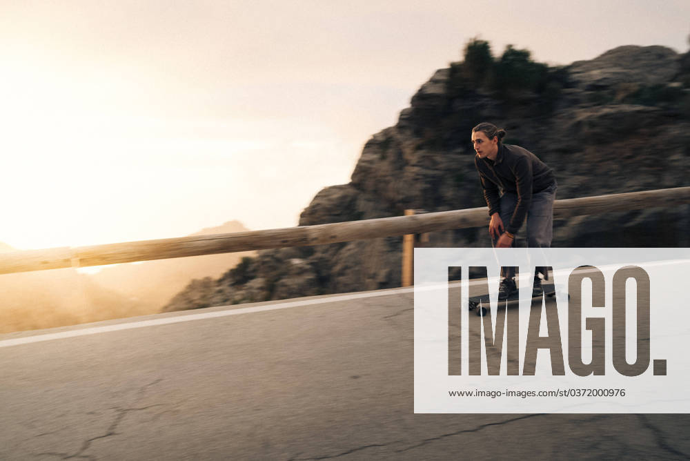 Man skateboarding near railing on road at sunset Spain, Mallorca, model released