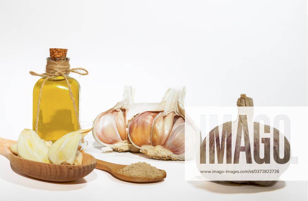 Ganzer, pulverisierter und gehackter Knoblauch auf weißem Hintergrund mit einer Glasflasche mit Olivenöl