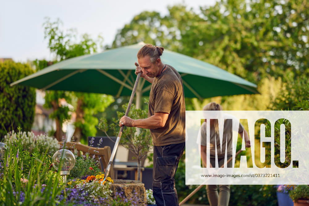Handwerker fegen die Terasse Male gardener raking the the flower bed while the collegue is sweeping the terrace in summer ,model released, Symbolfoto ,property released