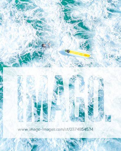 An overhead vertical shot of a surfer with a yellow surfboard in a blue sea 35571 RECORD DATE NOT STATED