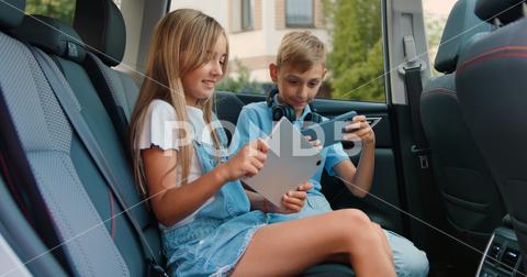 Attaractive boy and girl playing a tablet and smartphone in Car. Children using a devices for games and entertainment, traveling in auto. phone boy car traveling kid little girl trip playing happy sitting internet technology watching transportation travel cute gadget play family cheerful holding connection caucasian screen young mobile road automobile using adorable joy happiness brother game fun preteen cellphone modern asian bonding communication sister together seat tablet smartphone vehicle backseat