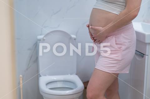 Pregnant woman holding her belly in the toilet. incontinence during pregnancy pregnant woman holding belly toilet incontinence during pregnancy pain care bathroom birth ache bladder childbirth constipation expecting fatigue hands cramp crotch control health healthcare hurt hurrying hygiene indigestion infection labor maternity mom mother pee pressure restroom problem rushing stomach suffer urgent urination weak home body symptom bad tummy