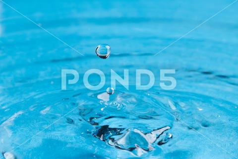 Close up of water drop falling into water with ripples and copy space on blue background. Water, liquid and colour concept. No People Close Water Drop Falling Water Ripple Copy Space Blue Background Liquid Colour Concept Drop Splash Abstract Design Background Wet Flow Fluid Closeup Wave Illustration Macro Business Graphic Symbol Isolated Flowing Color Clean Drink Water Falling Copy Space Blue
