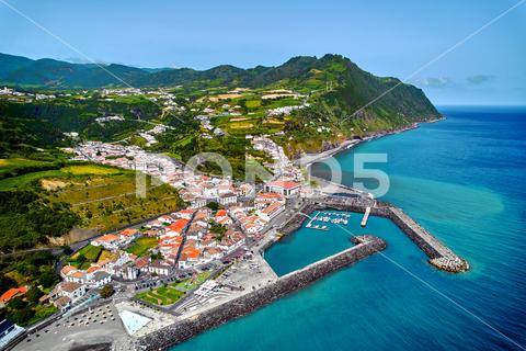 Aerial view Povoacao townscape, island of Sao Miguel in Portuguese archipelago of Azores. Marina with moored boats, town rooftops and surroundings green hills view from above. Ponta Delgada. Portugal azores sky resort beach harbor port marina rooftops village townscape town povoacao acores aerial archipelago atlantic beautiful coast coastline destination europe holiday idyllic island lagoon landmark landscape mountain nature ocean outdoors panorama panoramic ponta delgada portugal portuguese san miguel scene scenery seascape shore tourism tourist touristic travel view volcanic water