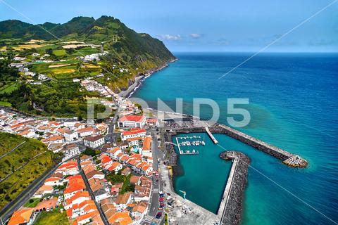 Aerial view Povoacao townscape, island of Sao Miguel in Portuguese archipelago of Azores. Marina with moored boats, town rooftops and surroundings green hills view from above. Ponta Delgada. Portugal azores sky resort beach harbor port marina rooftops village townscape town povoacao acores aerial archipelago atlantic beautiful coast coastline destination europe holiday idyllic island lagoon landmark landscape mountain nature ocean outdoors panorama panoramic ponta delgada portugal portuguese san miguel scene scenery seascape shore tourism tourist touristic travel view volcanic water