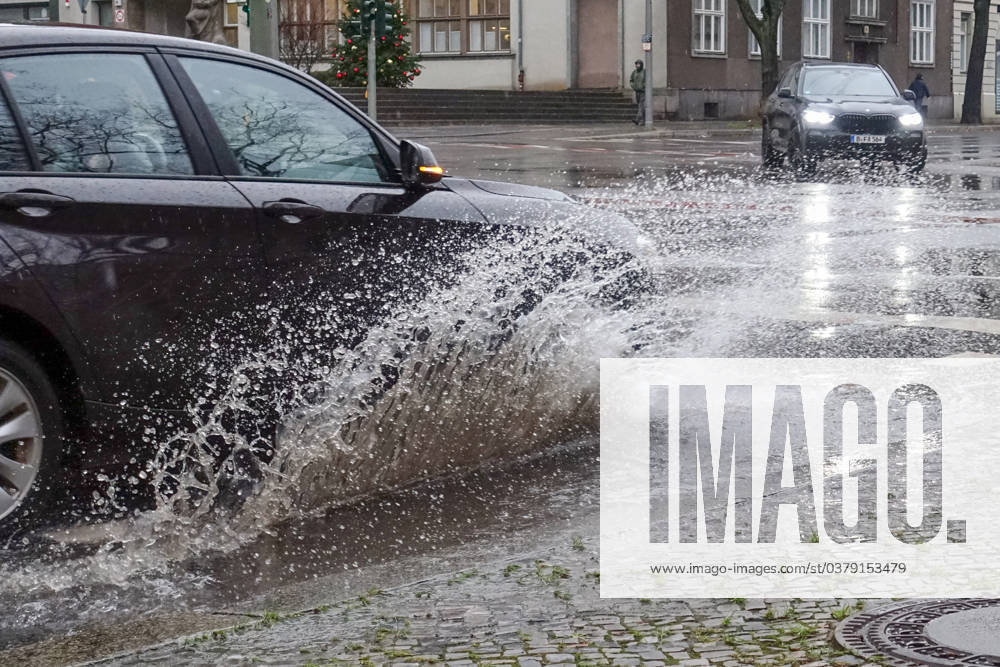 Berlin, GER - Auto faehrt auf einer Strasse durch eine grosse Pfuetze. (Alltag, Anschnitt, Aquaplaning, aussen, Aussenaufnahme, Automobile, Autos, Autoverkehr, Berlin, deutsch, Deutschland, Europa, europaeisch, Fahrbahn, fahren, Fahrzeuge, Individualverkehr, Jahreszeit, Kraftfahrzeuge, Naesse, nass, Personenkraftwagen, Pfuetze, PKW, QF, Querformat, Regen, Regenwetter, regnerisch, Schlechtwetter, Spritzwasser, Strasse, Strassenszene, Strassenverkehr, ueberflutet, Ueberflutung, Verkehr, verregnet, Wasser, Wasserlache, Wasserspritzer, Westeuropa, Wetter, Wetterlage, Winter) 231221D808BERLIN