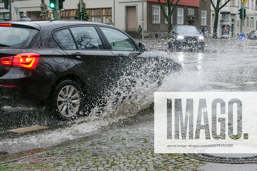 Berlin, GER - Auto faehrt auf einer Strasse durch eine grosse Pfuetze. (Alltag, Anschnitt, Aquaplaning, aussen, Aussenaufnahme, Automobile, Autos, Autoverkehr, Berlin, deutsch, Deutschland, Europa, europaeisch, Fahrbahn, fahren, Fahrzeuge, Individualverkehr, Jahreszeit, Kraftfahrzeuge, Naesse, nass, Personenkraftwagen, Pfuetze, PKW, QF, Querformat, Regen, Regenwetter, regnerisch, Schlechtwetter, Spritzwasser, Strasse, Strassenszene, Strassenverkehr, ueberflutet, Ueberflutung, Verkehr, verregnet, Wasser, Wasserlache, Wasserspritzer, Westeuropa, Wetter, Wetterlage, Winter) 231221D809BERLIN