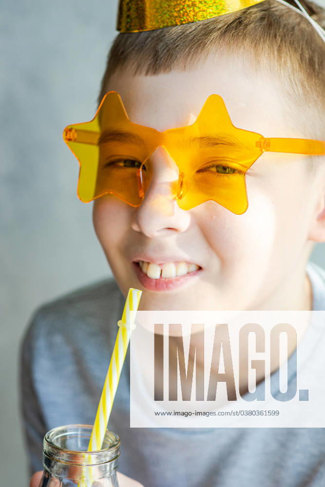 IMAGO Creative, Gesellschaft, Fasching A young boy with a playful smile wearing star-shaped sunglasses and drinking from a straw. Model Released AnnaBogush_ID18228_545531_001