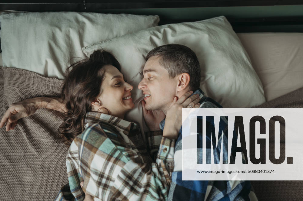 Woman embracing man lying on bed at home model released, Symbolfoto property released, ANAF02512