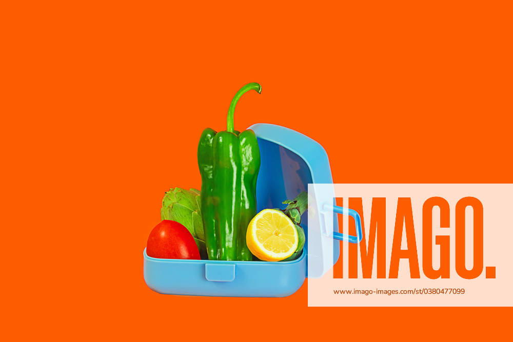 IMAGO Creative, Food, Trend, Meal Prep An open lunchbox filled with vibrant green bell peppers, lettuce, tomato, and a slice of lemon set against a contrasting orange backdrop. Model Released Rodobot_ID17553_531793_002