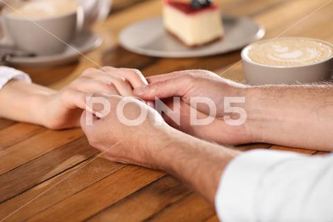 Romantic date. Couple holding hands together at wooden table in cafe, closeup adult background beautiful bonding boyfriend cafe cake cappuccino casual closeup coffee couple date dating enjoying enjoyment family feelings female flirt gently girlfriend hands holding indoors lifestyle love lovely lover lovers male man meet meeting people relationships restaurant romance romantic spending sweetheart table time together togetherness woman wooden