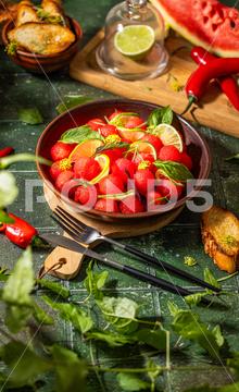 Spicy salad of fresh watermelon balls with basil, lime, rosemary and fennel, topping with olive oil on dark green table surface with sunny light watermelon vegetable summer food healthy salad basil lime rosemary freshness delicious cheese melon table organic epicure vegetarian plate fruit dinner meal sweet green diet red lunch fresh leaf juicy ripe snack herb closeup rustic overhead nourishment eating dish cookery