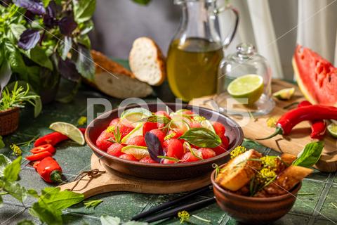 Spicy salad of fresh watermelon balls with basil, lime, rosemary and fennel, topping with olive oil on dark green table surface with sunny light watermelon vegetable summer food healthy salad basil lime rosemary freshness delicious cheese melon table organic epicure vegetarian plate fruit dinner meal sweet green diet red lunch fresh leaf juicy ripe snack herb closeup rustic overhead nourishment eating dish cookery