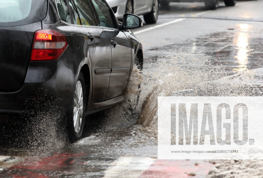 VYSHNEVE, UKRAINE - JANUARY 04, 2024 - A car drives through a deep puddle on the street, Vyshneve, Kyiv region, north-central Ukraine Wintertime in Vyshneve