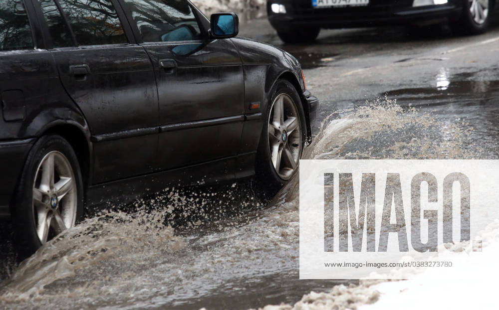 VYSHNEVE, UKRAINE - JANUARY 04, 2024 - A car drives through a deep puddle on the street, Vyshneve, Kyiv region, north-central Ukraine Wintertime in Vyshneve
