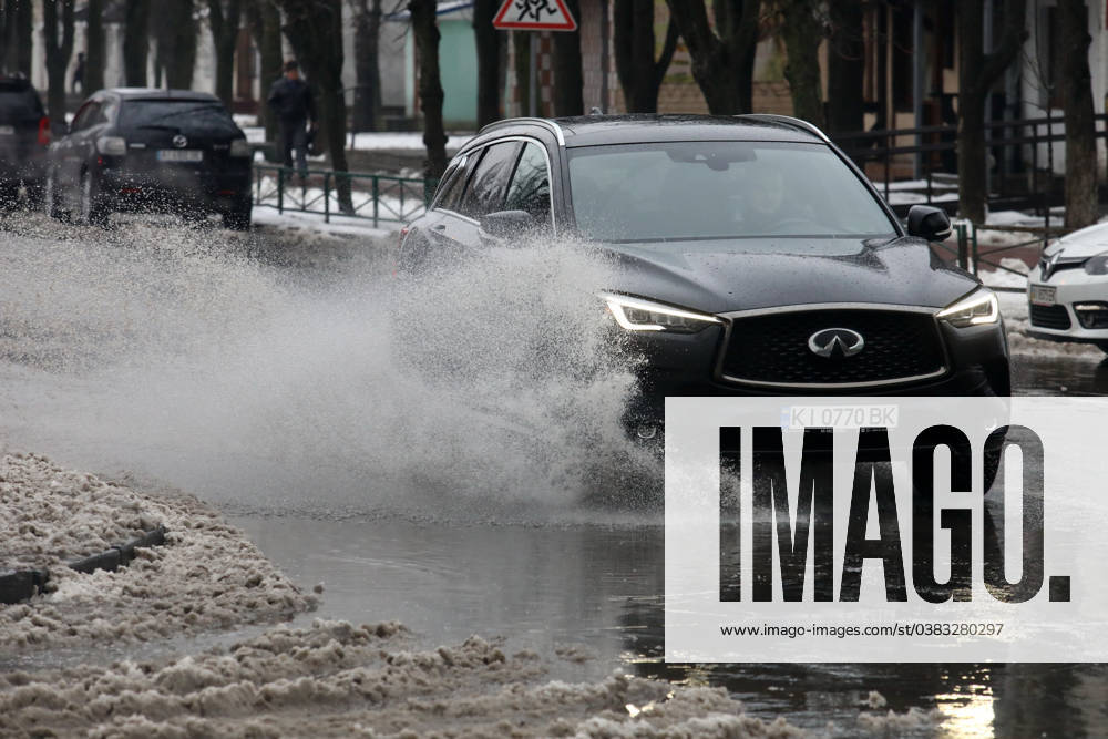 VYSHNEVE, UKRAINE - JANUARY 04, 2024 - A car drives through a deep puddle on the street, Vyshneve, Kyiv region, north-central Ukraine Wintertime in Vyshneve