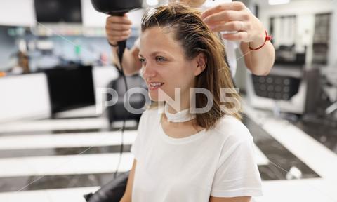 Woman in a beauty salon dry her head with hairdryer. Hair styling training concept woman portrait hairdryer master wet hair hairdresser beauty salon training hairstyles styling workplace hairstylist professional style fashion stylist studio grooming concept closeup haircut comb wig bob bangs curls strands hairbrush drying hairstyle curling air shampooing shampoo client visitor service hold people customer work equipment straight glamour barber beautiful services