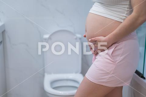 Pregnant woman holding her belly in the toilet. incontinence during pregnancy pregnant woman holding belly toilet incontinence during pregnancy pain care bathroom birth ache bladder childbirth constipation expecting fatigue hands cramp crotch control health healthcare hurt hurrying hygiene indigestion infection labor maternity mom mother pee pressure restroom problem rushing stomach suffer urgent urination weak home body symptom bad tummy