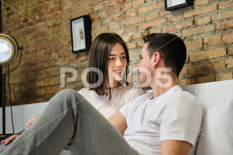 Romantic young couple looking each other while relaxing on bed at home woman man couple adult young caucasian two person morning lifestyle indoors home looking 25-30 years millenial casual clothing leisure activity brown hair everyday life heterosexual couple girlfriend love care romance boyfriend domestic bedroom two people male female caucasian ethnicity 0-6 month old 21-25 years old