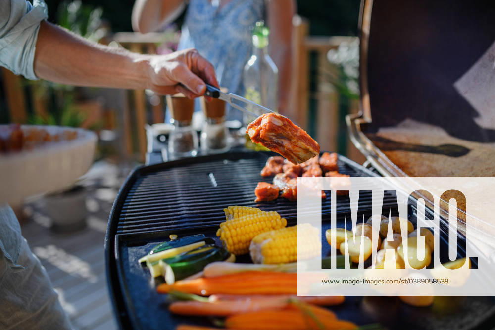 Unrecognizable man grilling ribs and vegetable on grill during family summer garden party, close-up An unrecognizable man grilling ribs and vegetable on grill during family summer garden party model released