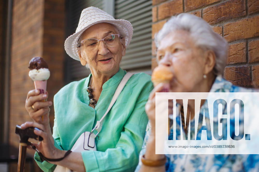 Portrait of two senior female friends in the city, eating ice cream on a hot summer day. Portrait of two senior female friends in the city, eating ice cream on a hot summer day. Elderly ladies on summer vacation in the city. Pensioners on group trip. Concept of senior vacation and travel groups, clubs. model released
