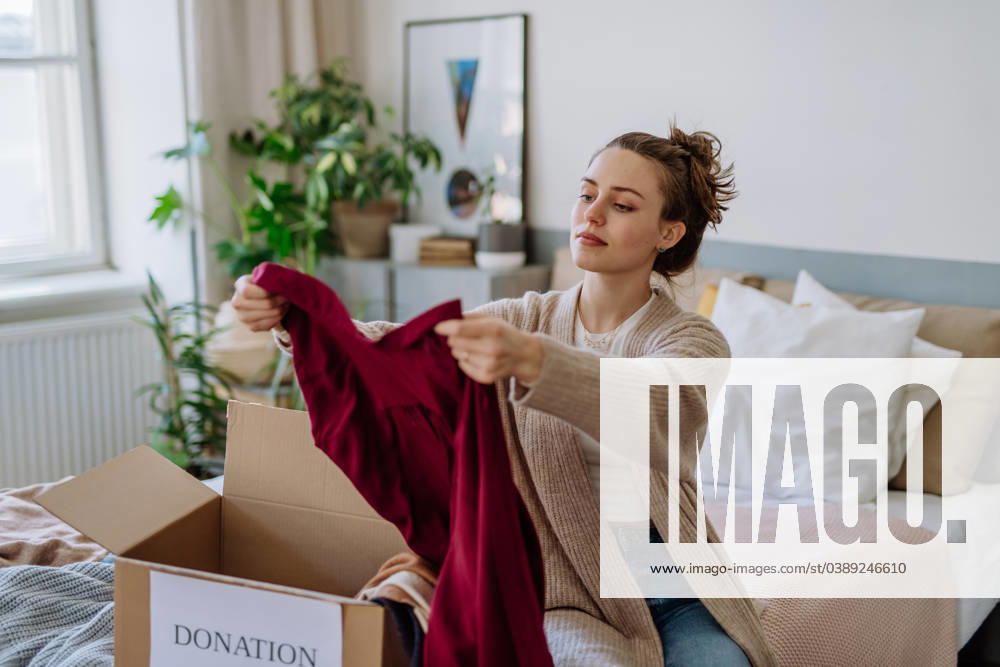Young woman giving her clothes to charity. Young woman giving her clothes packed in box to charity. model released