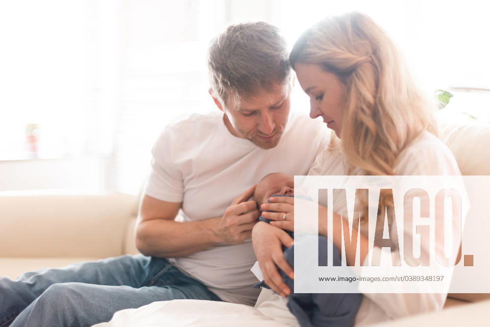 Smiling mother and father holding their newborn baby boy at home A smiling mother and father holding their newborn baby daughter at home model released