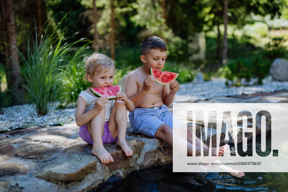 Little chidren sitting near lake and eating watermelon on hot sunny day during summer vacation. Little chidren sitting near a lake and eating watermelon on hot sunny day during summer vacation. model released