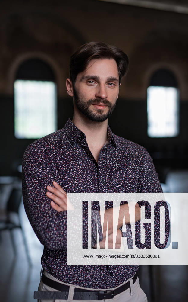 Portrait of young businessman standing indoors in office, looking at camera. A portrait of young businessman standing indoors in office, looking at camera. model released