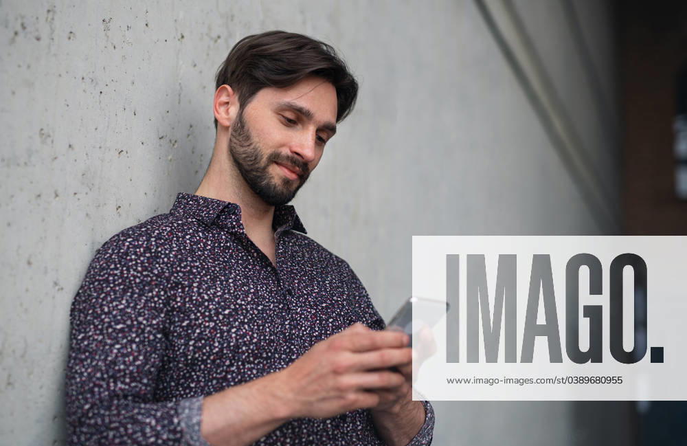 Portrait of young businessman standing indoors, using smarpthone. A portrait of young businessman standing indoors, using smarpthone. model released
