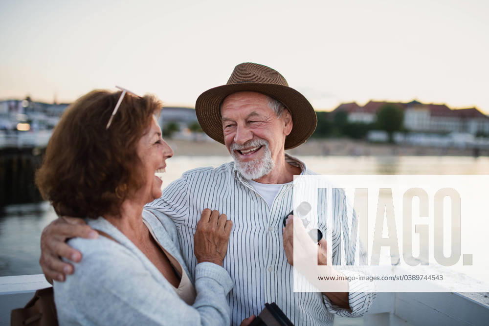 Happy senior couple hugging outdoors on pier by sea, looking at each otherand laughing. Happy senior couple in love hugging outdoors on pier by sea, looking at each otherand laughing. model released