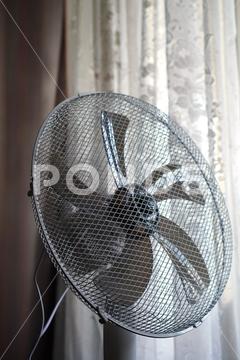 Vertical photo with a large fan with blades and a metal grille on the background of a window with tulle curtains the concept of indoor climate control in summer during the heat. large fan blades metal grille background window tulle curtains concept indoor climate control summer during heat air blade conditioning apartment cooling cool fashion blower blow circulation condition decoration home furniture decor curtain floor electric object office relax conditioner decorating house indoors rotation residential ventilator parquet vent textile temperature interior domestic
