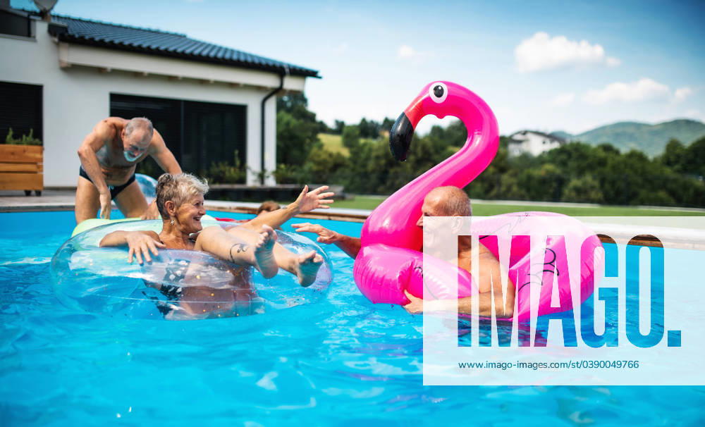Group of cheerful seniors in swimming pool outdoors in backyard, talking. Group of cheerful seniors in swimming pool outdoors in backyard, talking and having fun. model released