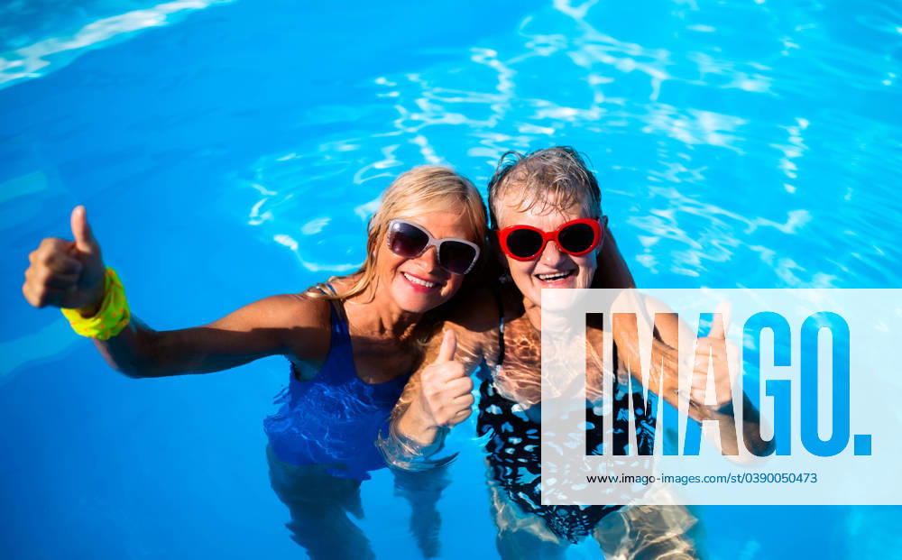 High angle view of cheerful senior women in swimming pool outdoors in backyard. High angle view of cheerful senior women in swimming pool outdoors in backyard, looking at camera. model released