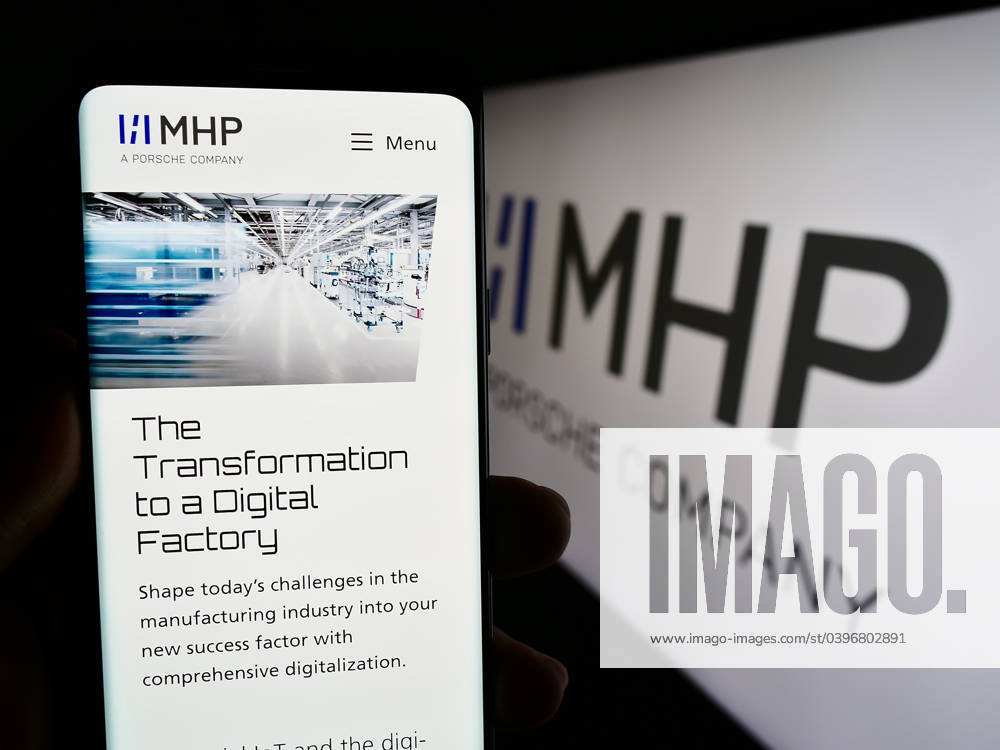 Person holding cellphone with webpage of company MHP Management- und IT-Beratung GmbH on screen. Stuttgart, Germany - 08-20-2023: Person holding cellphone with webpage of company MHP Management- und IT-Beratung GmbH on screen with logo. Focus on center of phone display.