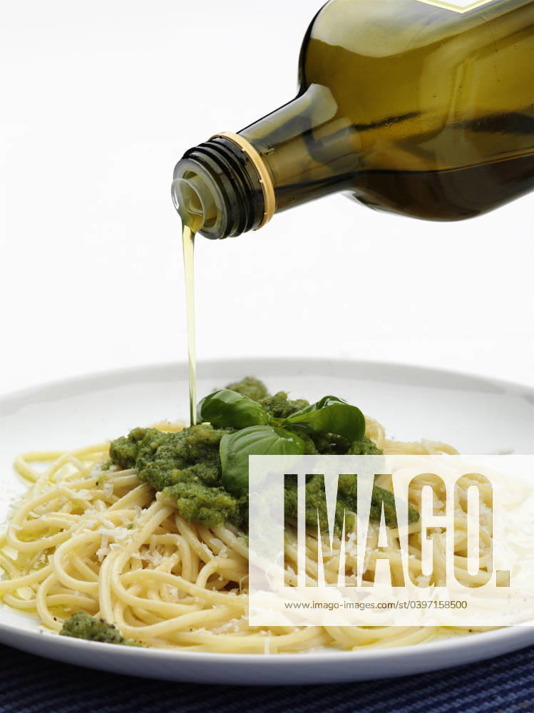 Bottle of olive oil pouring over plate of pesto pasta Milan, Lombardy Metro City of Milan, Italy, 21.12.2023, TTBB_BLD185626.jpg, bottle, close up, color image, copy space, focus on foreground, food and drink, leaf, motion, nobody, oil, olio, olive oil, pasta, pesto, photography, plate, pouring, spaghetti, spaghetti al pesto, studio shot, vertical, white background, carbohydrate, close-up, closeup, color, colour, container, crockery, dish, dishware, foliage, food, italian, movement, negative space, plant, pour, studio, tableware, vegetation, white space,