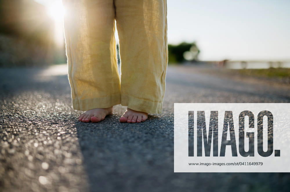 Close up of girl s barefoot legs in summer outfit on walk during summer vacation, yellow linen pants. Close up of girl s barefoot legs in summer outfit on walk during summer vacation, wearing yellow linen pants. model released