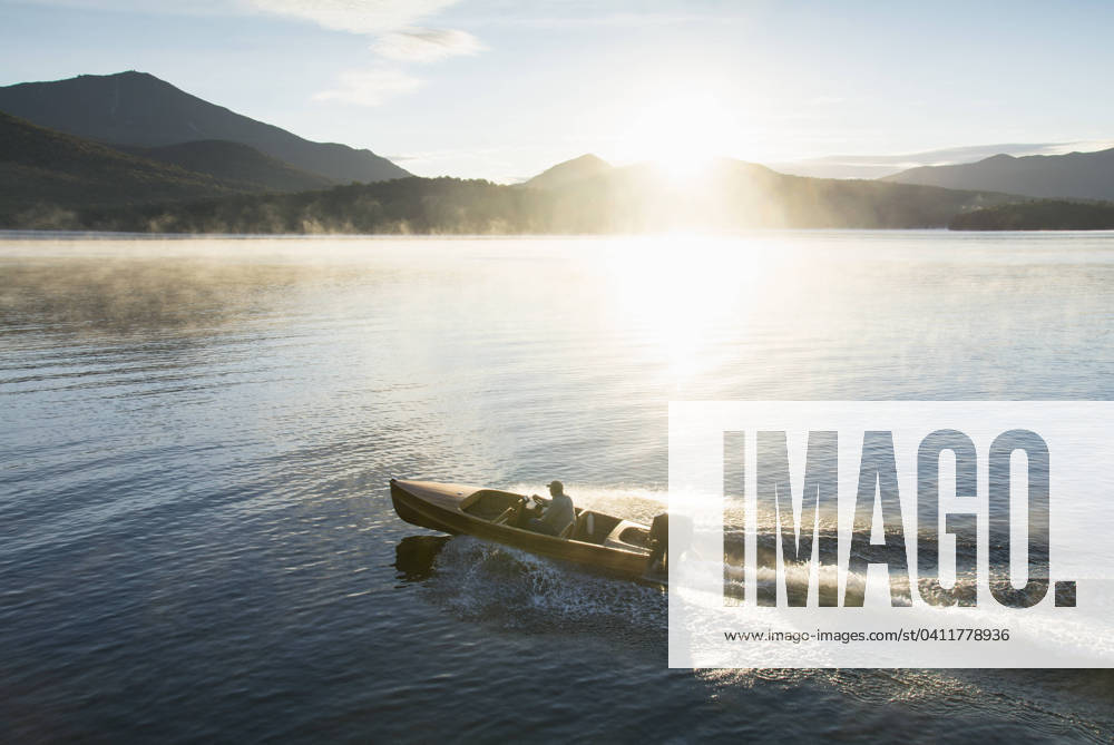 USA, New York, Lake Placid, Man in motorboat on Lake Placid , 22.09.2016, model released, TTBB_ti0027_00716.jpg, Lake, Caucasian Ethnicity, Motorboat, Outdoors, Day, Getting Away From It All, Summer, Vacations, Tranquility, Horizontal, Sun, Scenics, Fog, Mountain Range, On The Move, Travel Destinations, Morning, Lake Placid, Leisure Activity, Wake - Water, Solitude, Reflection, Speed, One Person, One Senior Man Only, 65-69 Years, USA, New York