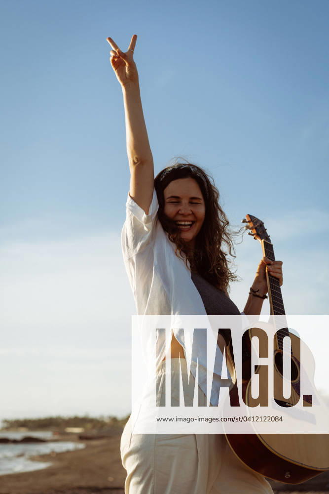 IMAGO Creative, Jahreszeit Sommer, Sommerferien Woman musician sings and plays guitar on the beach. In a bandana. Bali Kuta, Bali, Indonesia CR_YUKI240206-1331627-01 ,model released, Symbolfoto