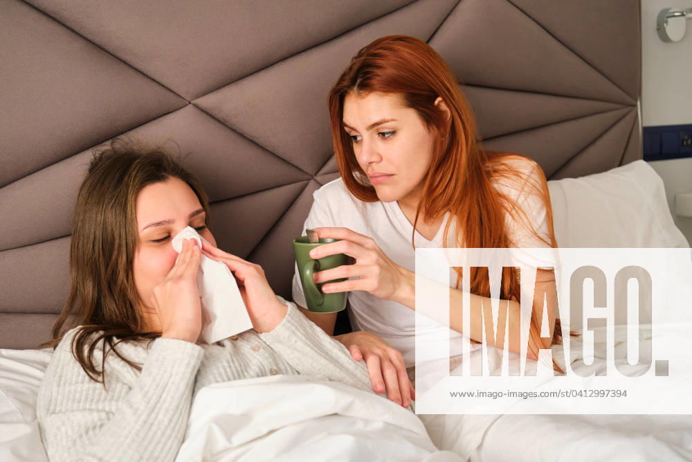 IMAGO Creative, Gesellschaft, Leisure Sickness Brazilian woman blowing her nose in a tissue while her wife take care. Madrid, Community of Madrid, Spain CR_CRVI240209-1349007-01 ,model released, Symbolfoto